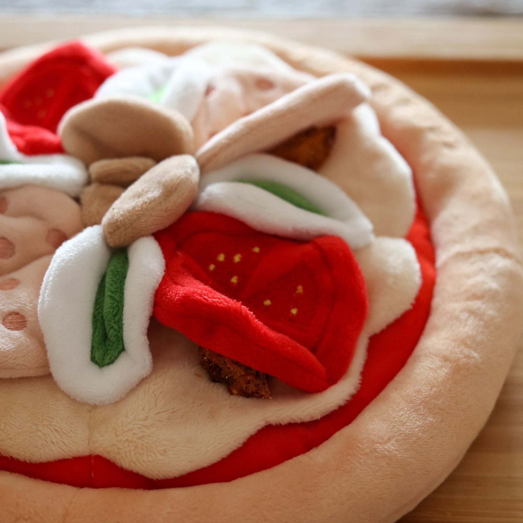 Close-up details of a hidden dog kibble reward inside the plush fabric layers of a pizza snuffle mat, designed as a slow feeder and boredom buster for pets.