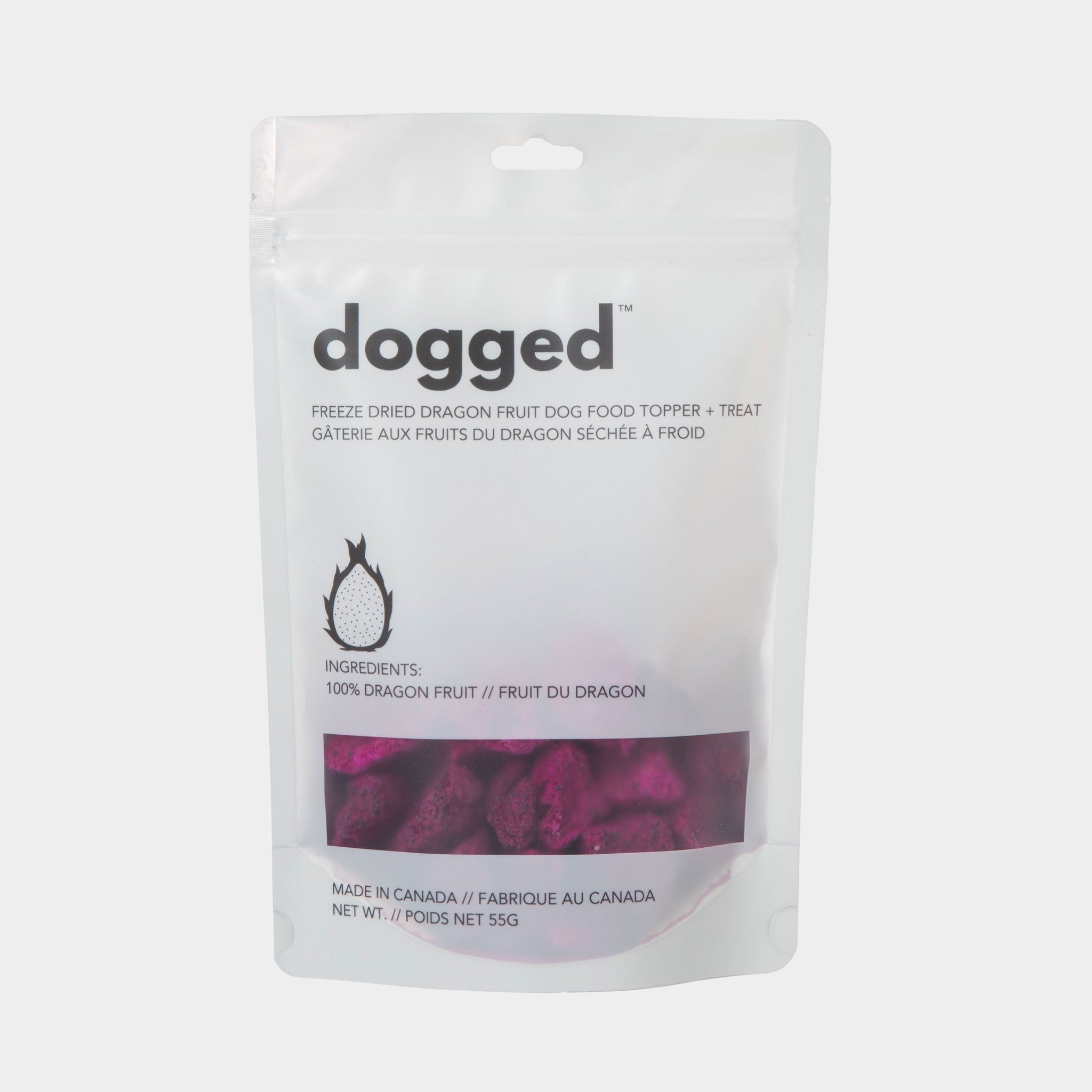 A full front studio shot of the Dogged 55g freeze-dried dragon fruit dog food topper packaging, showcasing the clean white minimalist design, bilingual English and French text, and a clear window showing the dried fruit inside.