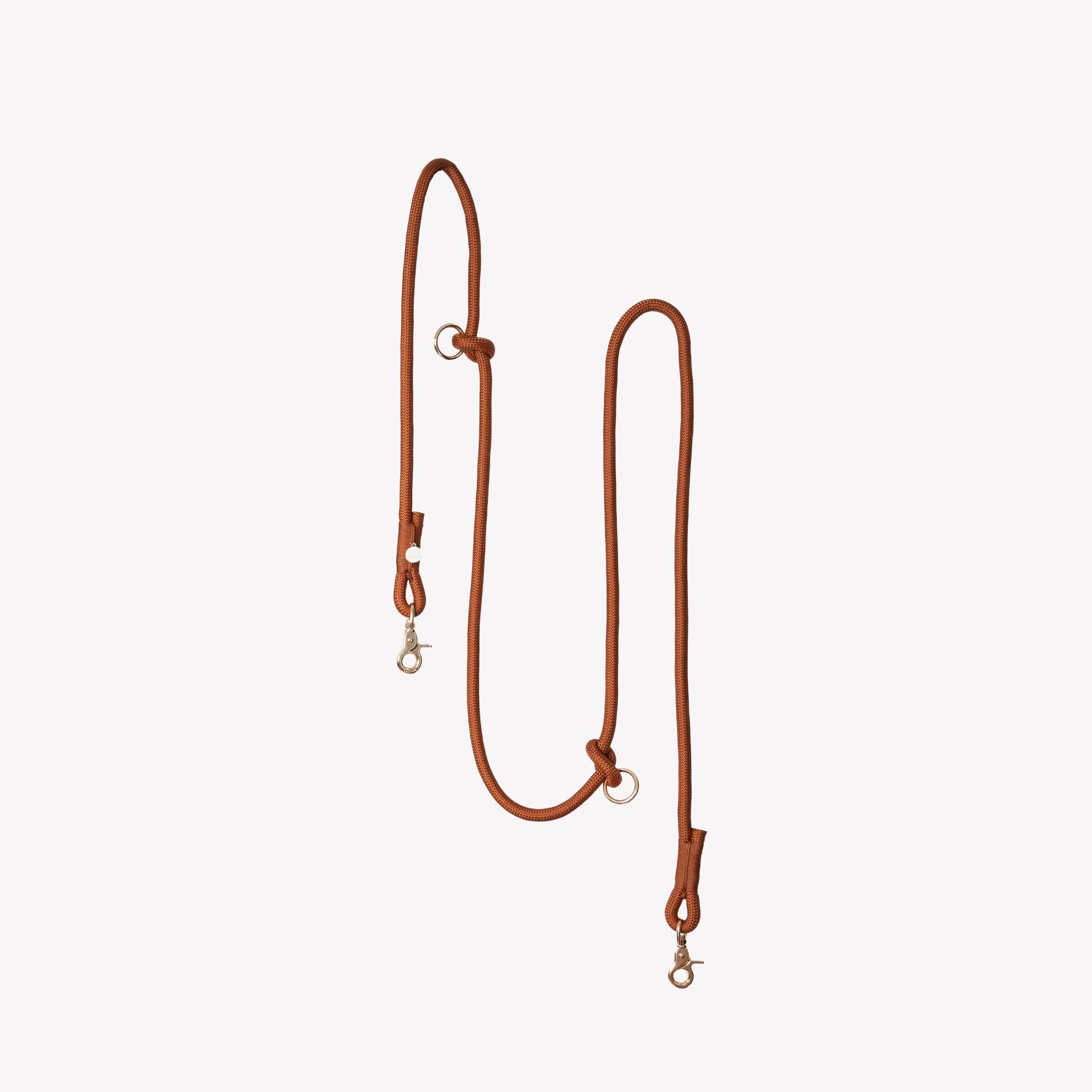 A vertical studio shot of the Clay colored Furlou braided hands-free dog leash, featuring high-quality hardware and adjustable rings against a clean white background.