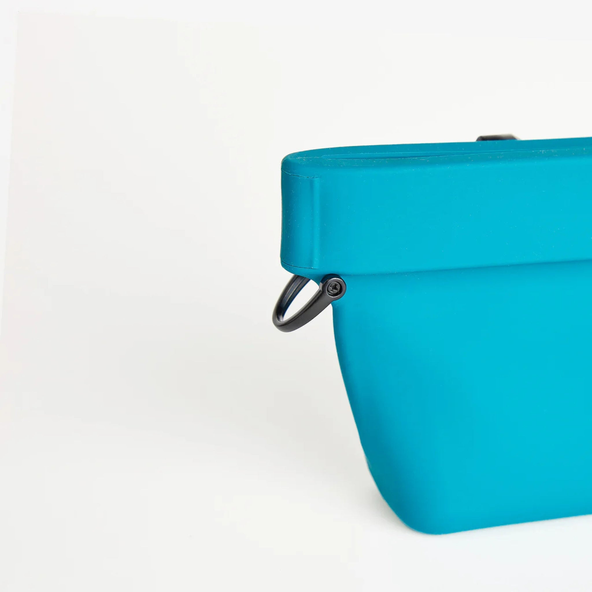 Close-up detail of the durable black D-ring attachment on the side of the turquoise silicone dog training pouch by Voilapets.