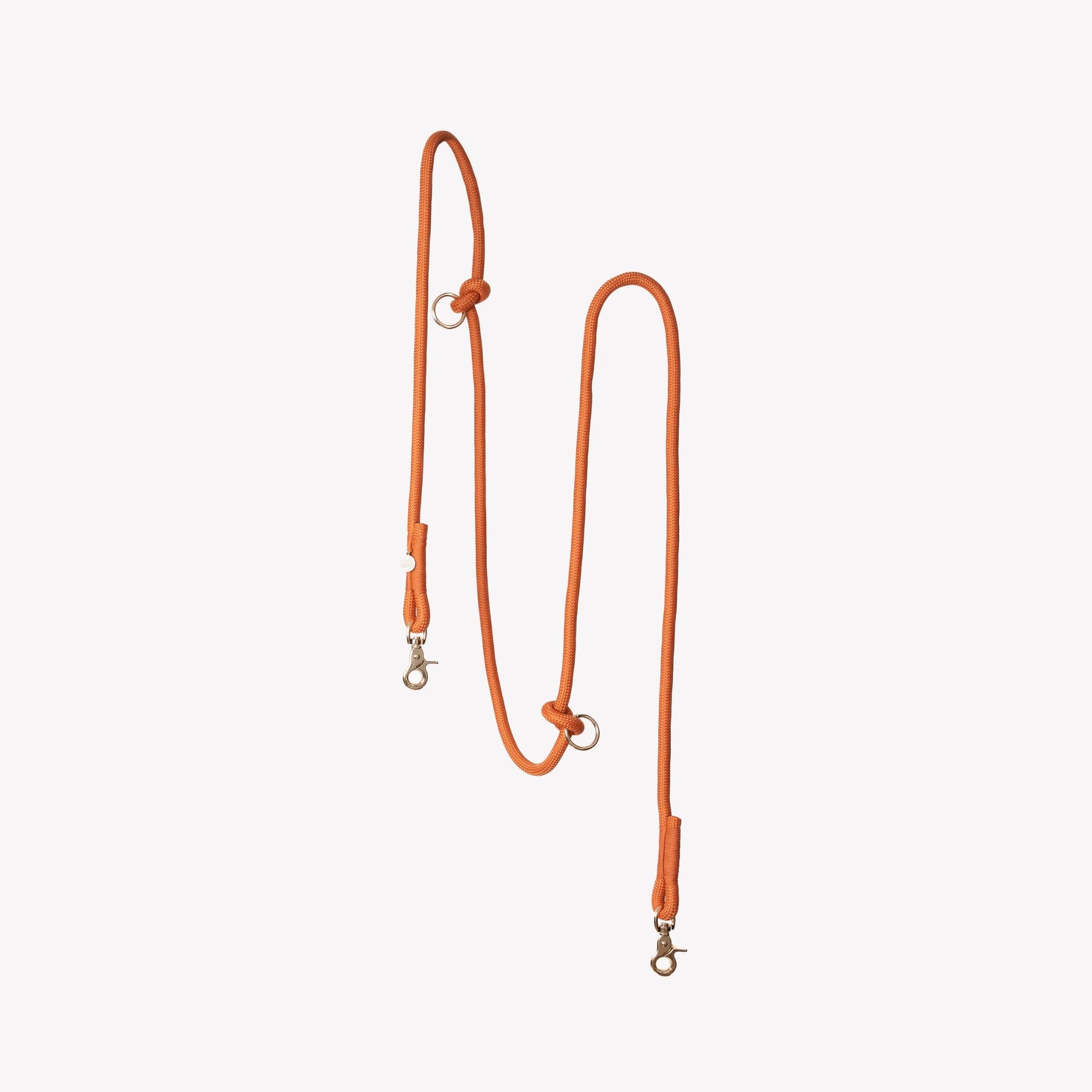 A vertical studio shot of the Terracotta colored Furlou braided hands-free dog leash, showcasing its adjustable rings and premium hardware against a plain background.