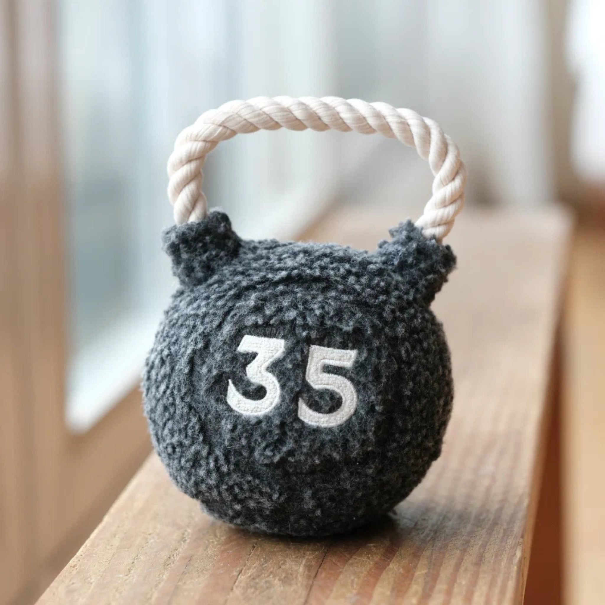 Lambwolf Collective Kettlebell plush dog toy with rope handle displayed indoors