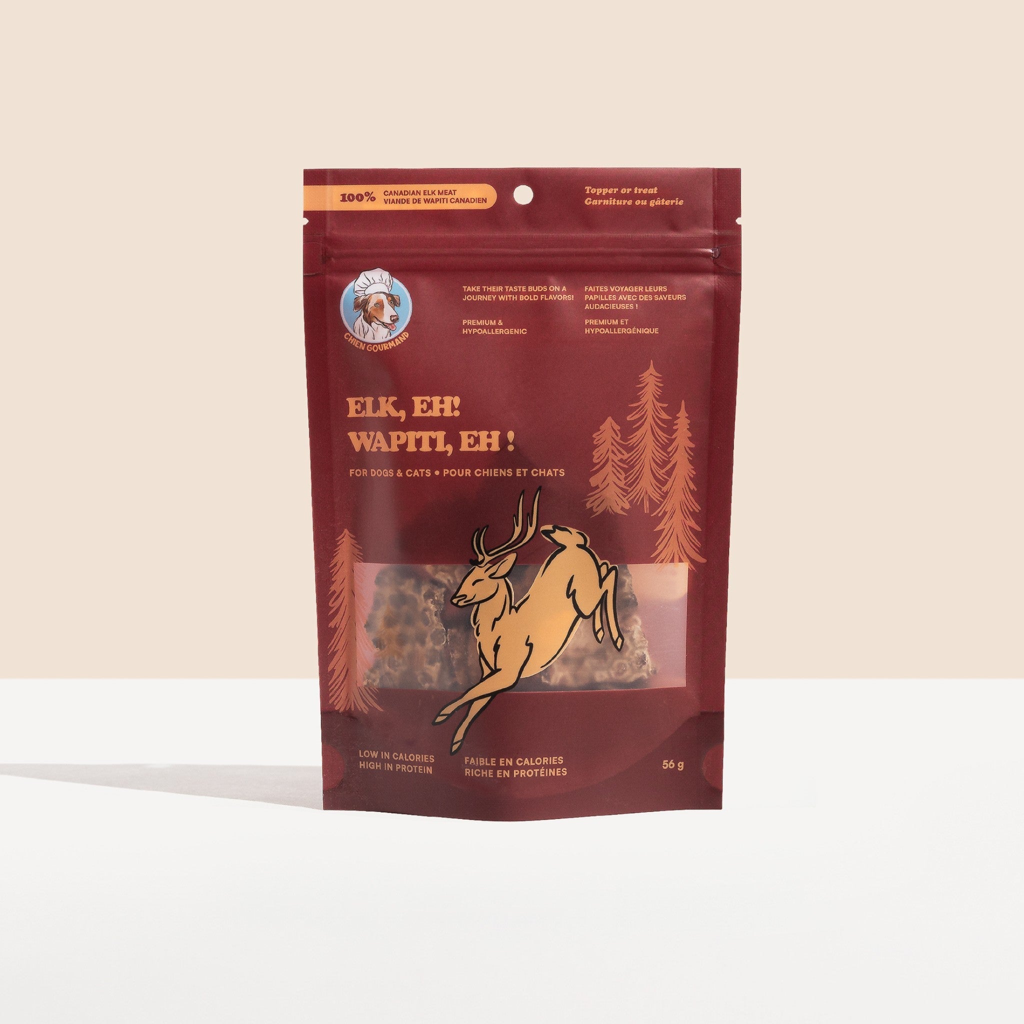 A studio shot of a 56g dark red stand-up pouch for Chien Gourmand Elk, Eh! Wapiti, Eh! freeze-dried dog and cat treats, featuring a clear window and an illustration of a jumping elk.