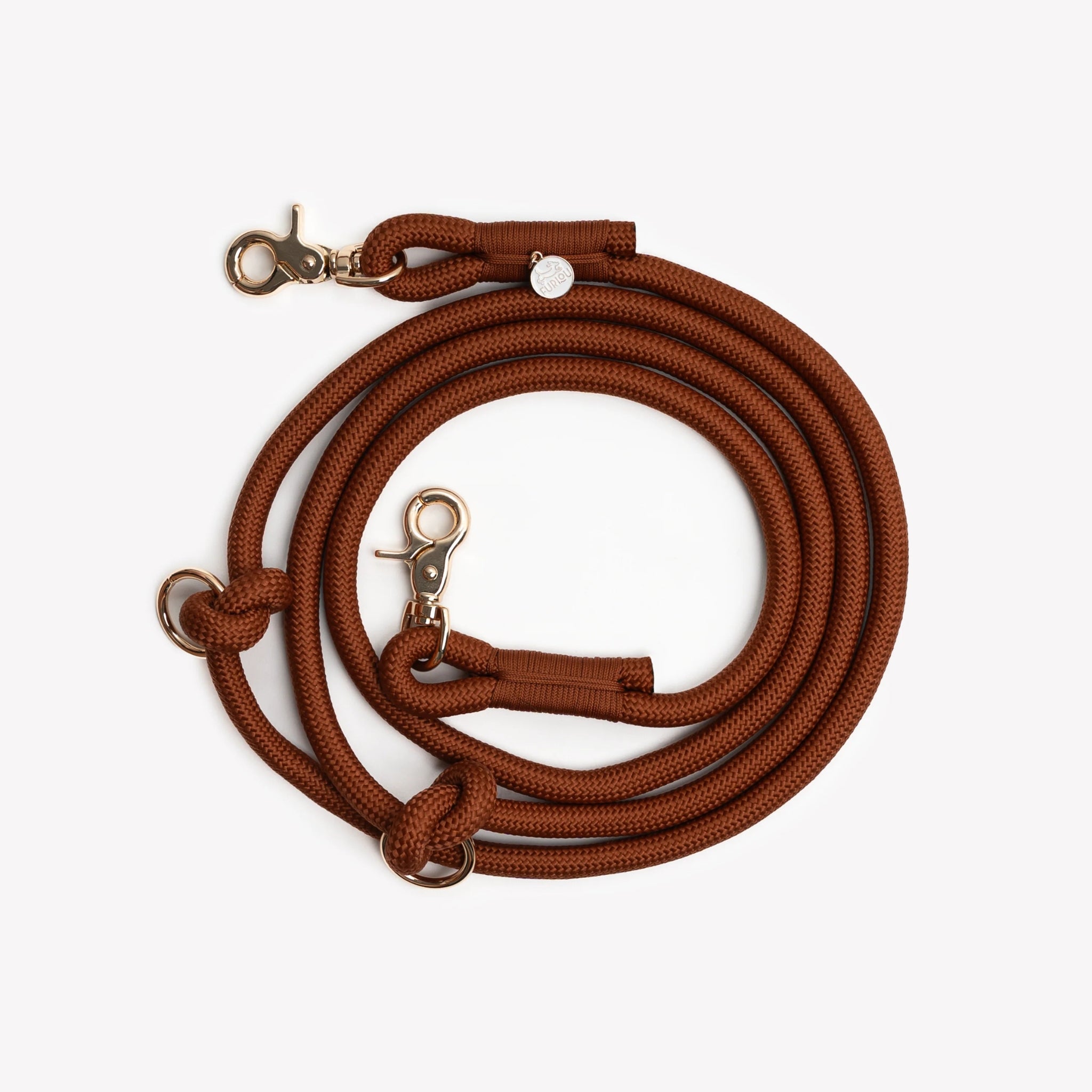 The Clay hands-free braided leash by Furlou coiled into a circle, highlighting the durable braided material and secure gold-toned clasps.