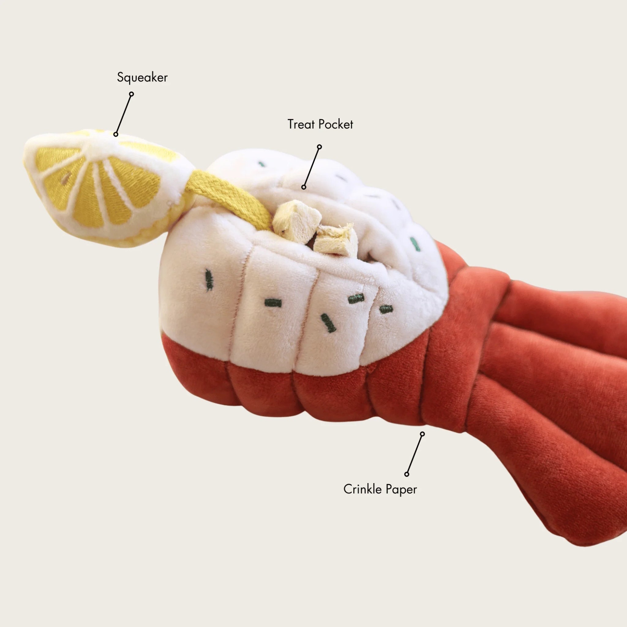 Product feature diagram of the Grilled Lobster interactive dog puzzle toy by Pups and Bubs, with labels pointing out the squeaker lemon, hidden treat pocket with snacks, and crinkle paper tail.